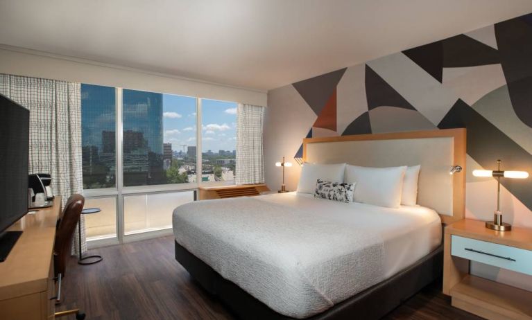 Double bed guest room in The Beeman Hotel, featuring large bed, and city view through the window.