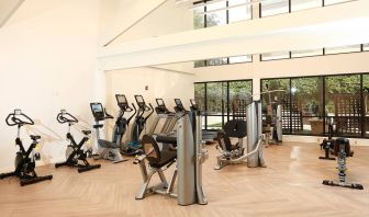 The hotel fitness center is brightly lit and has a broad selection of exercise machines.