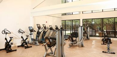 The hotel fitness center is brightly lit and has a broad selection of exercise machines.