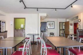 The hotel breakfast area has a hard floor and tables for two to four diners.