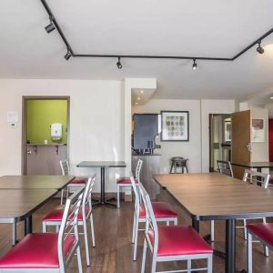 The hotel breakfast area has a hard floor and tables for two to four diners.