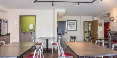 The hotel breakfast area has a hard floor and tables for two to four diners.