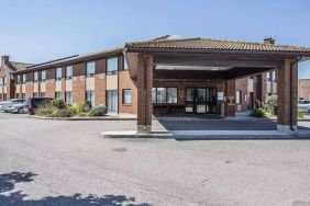 The entrance to Comfort Inn Gatineau is under cover, with nearby greenery and ample parking.