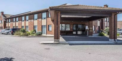 The entrance to Comfort Inn Gatineau is under cover, with nearby greenery and ample parking.