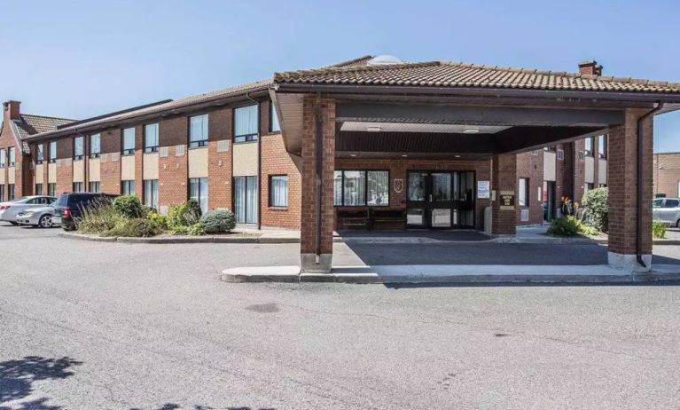 The entrance to Comfort Inn Gatineau is under cover, with nearby greenery and ample parking.