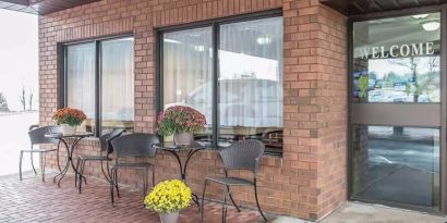 The hotel’s entrance is covered and has a nearby pair of small tables, each with two chairs.