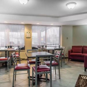 The hotel breakfast area has hard floors, small tables, and large windows.