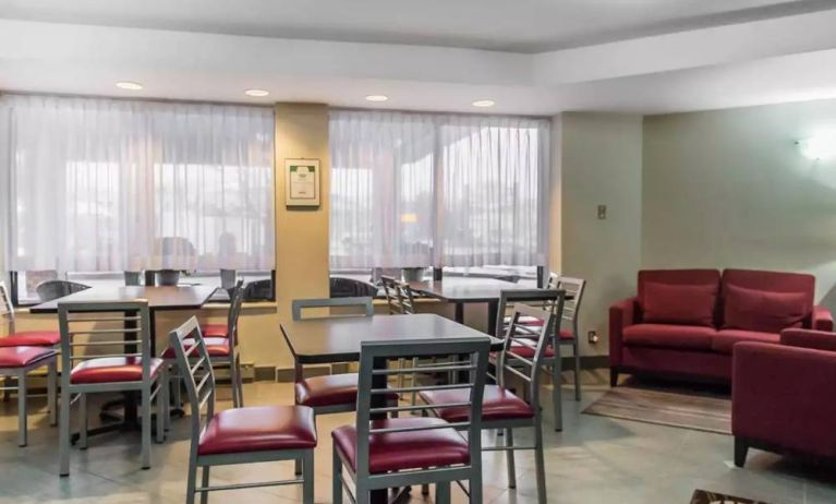 The hotel breakfast area has hard floors, small tables, and large windows.