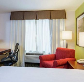 Guest room in Hilton Garden Inn Queens/JFK Airport with armchair and window.