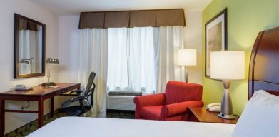 Guest room in Hilton Garden Inn Queens/JFK Airport with armchair and window.