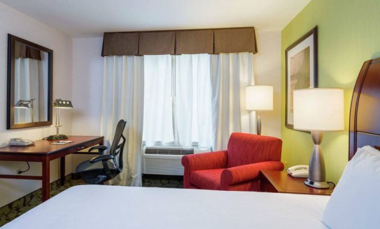 Guest room in Hilton Garden Inn Queens/JFK Airport with armchair and window.