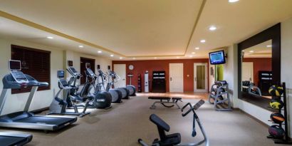 The hotel fitness center has racks of weights and assorted exercise machines.