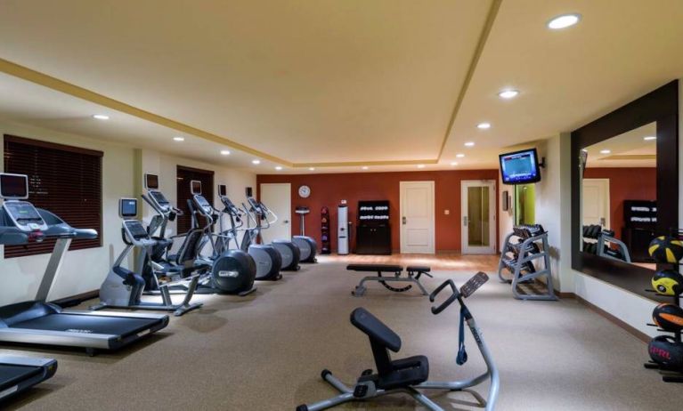 The hotel fitness center has racks of weights and assorted exercise machines.