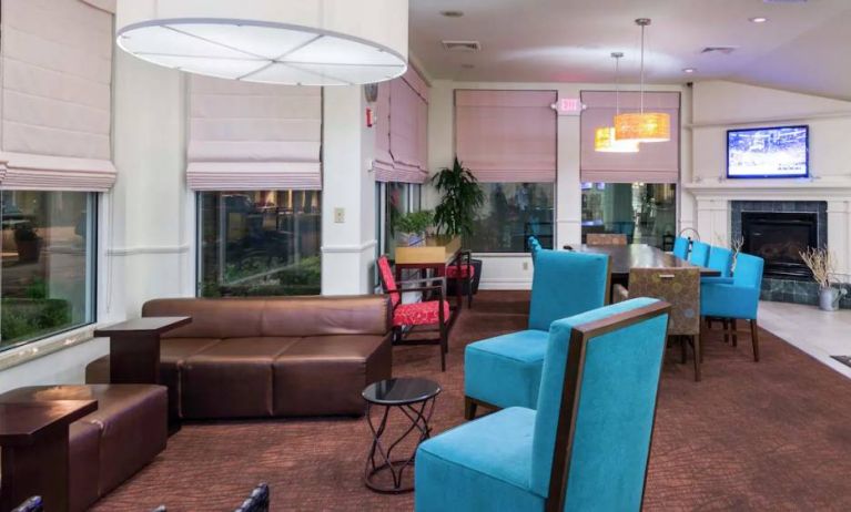 The lounge in the hotel lobby offers comfortable seating on chairs and sofas, with a large TV nearby.