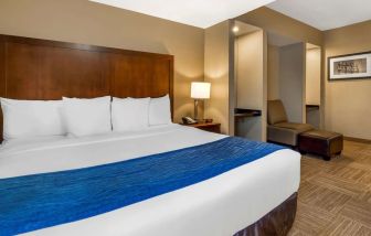 Spacious king bedroom with TV and work station at Comfort Inn & Suites Sea-Tac Airport.