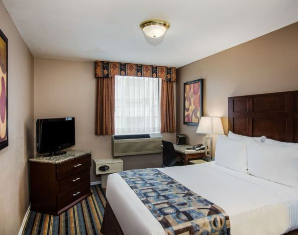 Spacious king bedroom with TV and work station at Ramada by Wyndham Vancouver Downtown.