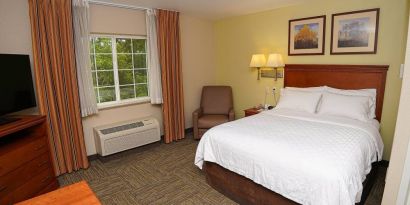 Double bed guest room in Candlewood Suites Boise, with window, armchair, and TV.