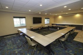 Hotel meeting room with four tables arranged in a square, and a large TV on the wall.