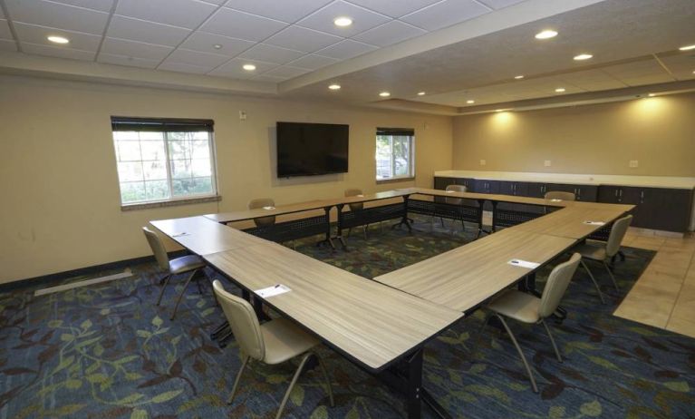 Hotel meeting room with four tables arranged in a square, and a large TV on the wall.