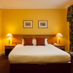 Single bed guest room in The Royal Highland Hotel, with bedside lamp and art on the wall.