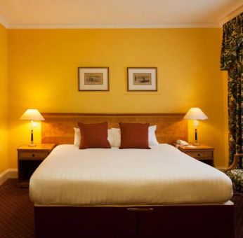 Single bed guest room in The Royal Highland Hotel, with bedside lamp and art on the wall.