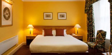 Single bed guest room in The Royal Highland Hotel, with bedside lamp and art on the wall.