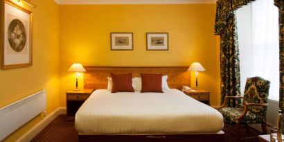 Single bed guest room in The Royal Highland Hotel, with bedside lamp and art on the wall.