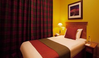 Single bed guest room in The Royal Highland Hotel, with bedside lamp and art on the wall.