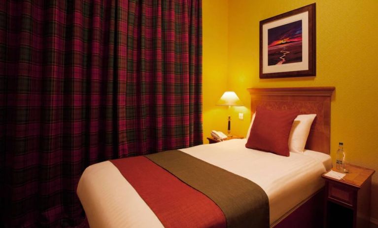 Single bed guest room in The Royal Highland Hotel, with bedside lamp and art on the wall.