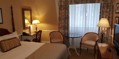 The Wall Street Inn guest room, featuring chairs, coffee table, and window.