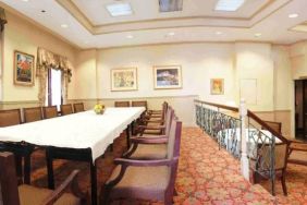 Hotel meeting room, with long table, surrounding chairs, and a large TV on the wall.