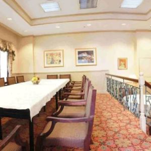 Hotel meeting room, with long table, surrounding chairs, and a large TV on the wall.