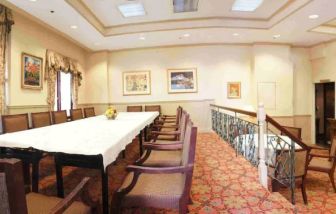 Hotel meeting room, with long table, surrounding chairs, and a large TV on the wall.