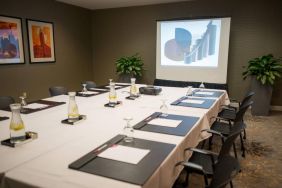 Executive meeting room with long table, surrounding chairs, and a projector screen.