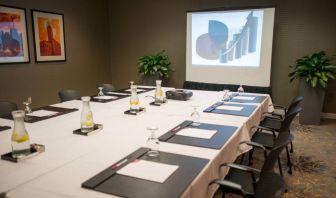 Executive meeting room with long table, surrounding chairs, and a projector screen.