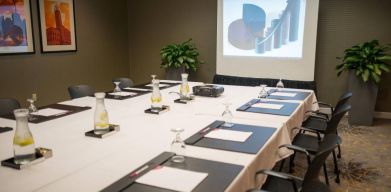 Executive meeting room with long table, surrounding chairs, and a projector screen.