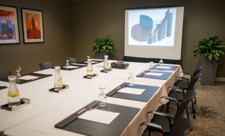 Executive meeting room with long table, surrounding chairs, and a projector screen.