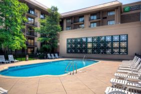 The hotel’s outdoor pool has nearby loungers, with trees offering shade from the sun.