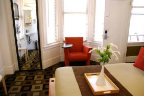 Guest room of The Mosser Hotel, with bed, chair, windows, and ensuite bathroom.