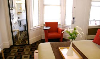 Guest room of The Mosser Hotel, with bed, chair, windows, and ensuite bathroom.