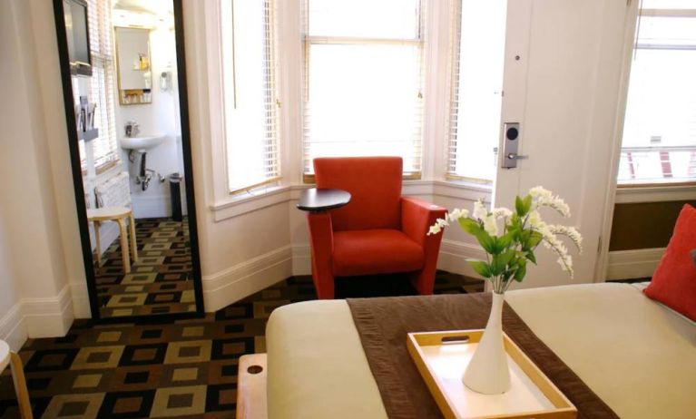 Guest room of The Mosser Hotel, with bed, chair, windows, and ensuite bathroom.