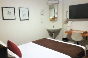 Guest room inside The Mosser Hotel, featuring a workspace desk and chair plus large TV.