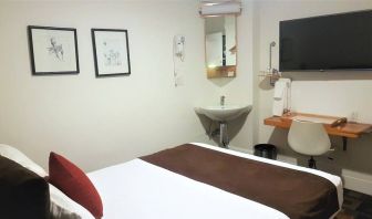 Guest room inside The Mosser Hotel, featuring a workspace desk and chair plus large TV.