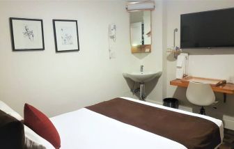 Guest room inside The Mosser Hotel, featuring a workspace desk and chair plus large TV.