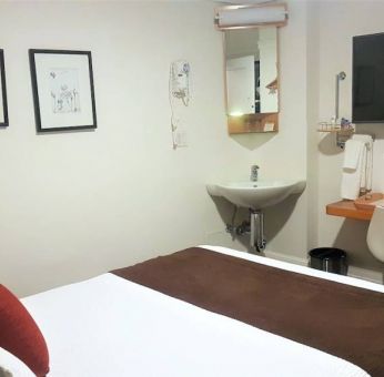 Guest room inside The Mosser Hotel, featuring a workspace desk and chair plus large TV.