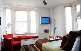 The Mosser Hotel guest room, including TV, chair, bed, and nearby window.