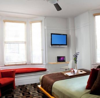 The Mosser Hotel guest room, including TV, chair, bed, and nearby window.