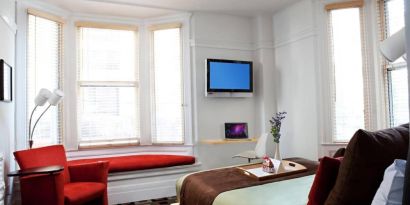 The Mosser Hotel guest room, including TV, chair, bed, and nearby window.