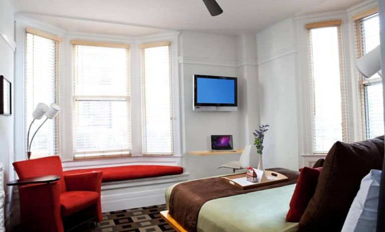 The Mosser Hotel guest room, including TV, chair, bed, and nearby window.