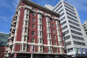 Exterior of the Mosser Hotel, with vertical sign and vibrant red brick hue.